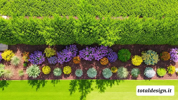 Vista dall'alto di bordura da giardino con catalpa alta sullo sfondo e fiori colorati e graminacee in primo piano