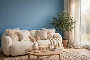 Soggiorno cozy con parete colore avio pulita, divano bouclé bianco e tavolino rovere con candele