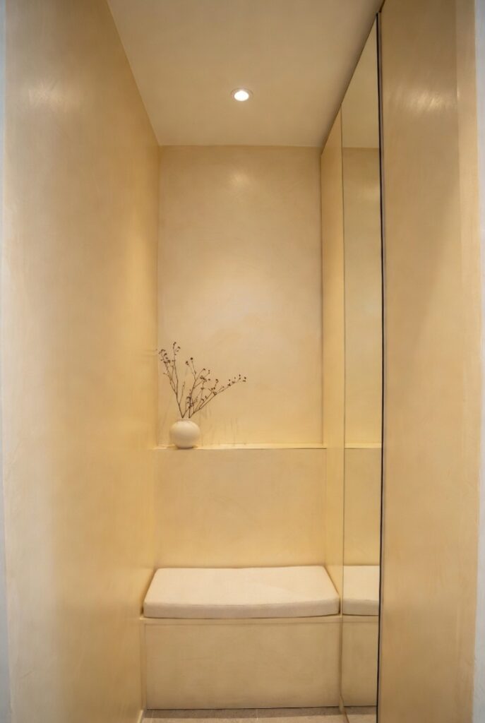 Effetto scatola ingresso beige avorio per spazi piccoli senza finestre, specchio alto riflettente, mensola ramo secco, panca e faretti luce diffusa 