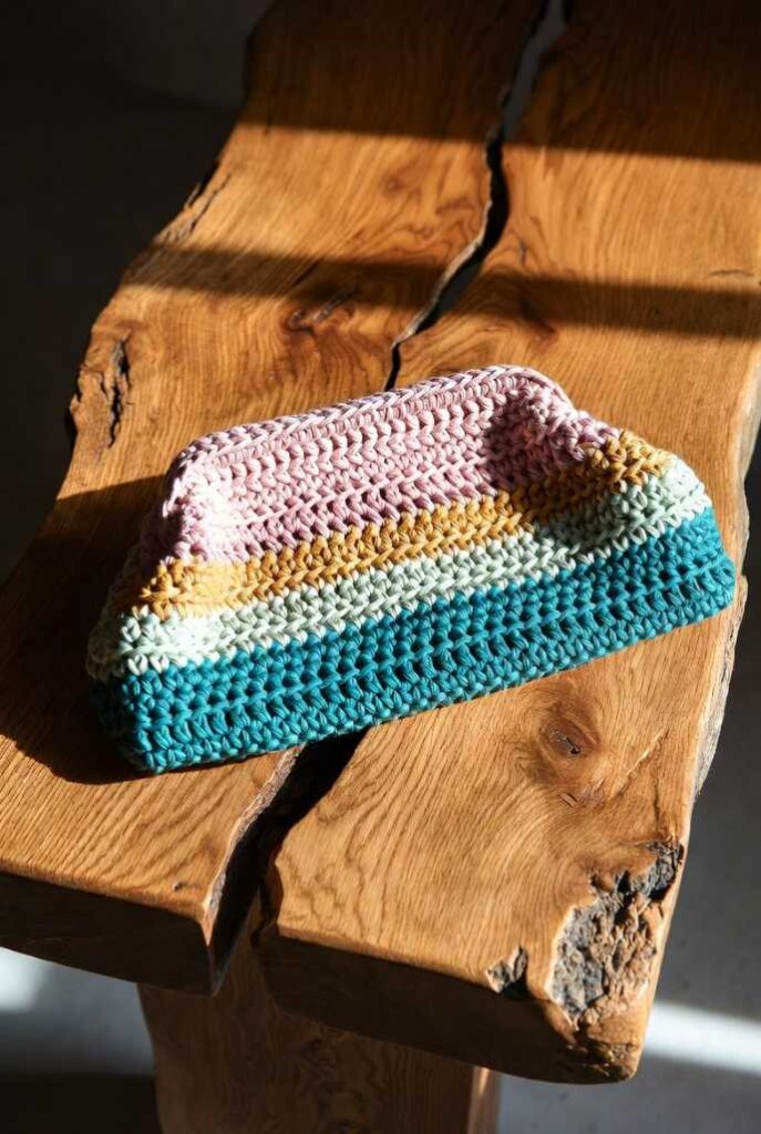 Borsa uncinetto fatta a mano clutch rigida multicolore rosa arancio verde texture crochet su tavolo legno venato luminoso