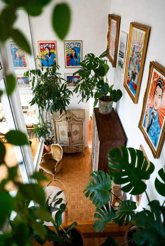 Open space con pezzi antichi limitati, piante monstera e stampe pop art in cornici dorate: usa lo spazio per abbinare arredamento antico e moderno.