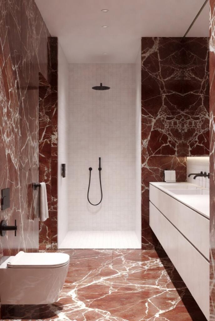 Arredamento bagno di lusso moderno con pareti e pavimenti in marmo rosso a venature bianche, vasca scultorea, doccia con mosaico e lavabo integrato in pietra naturale.