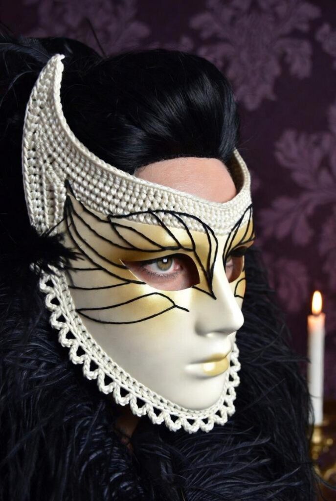 Maschera Bauta mistero veneziano crochet bianco perla opaco con profilo aguzzo mascella, bordi dentellati picot, doppio strato rigido, linee nere ombre viso, indossata da donna 35 anni pelle chiara capelli neri raccolti, illuminazione candele soffusa, sfondo damasco viola scuro specchi antichi piume nere, stile Carnevale veneziano enigmatico artigianale