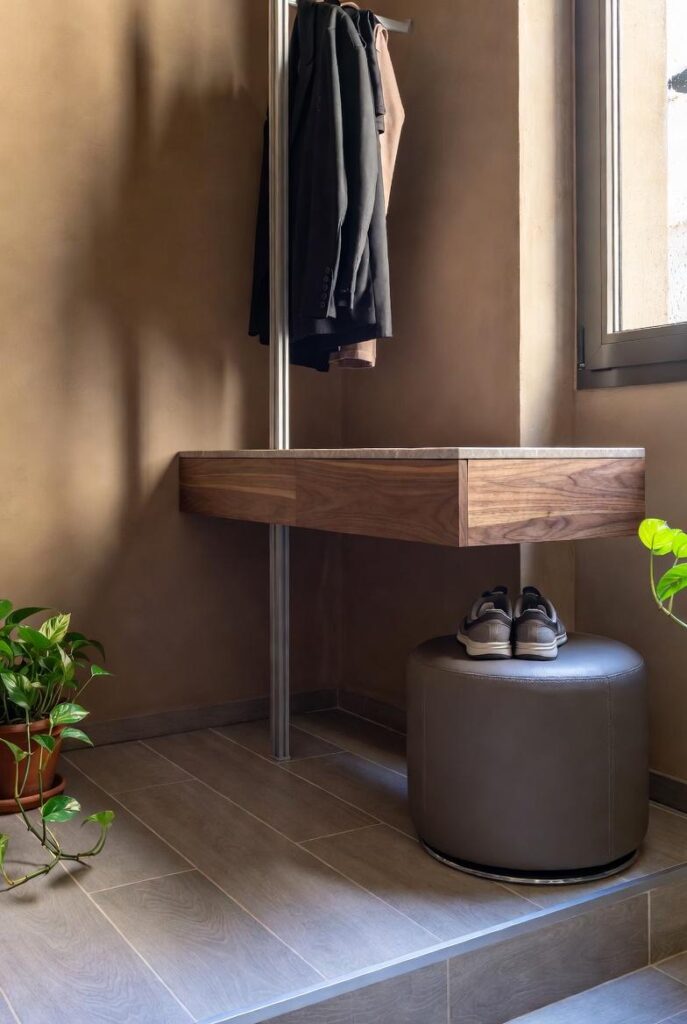 Trasformazione ingresso a due livelli monolocale milanese con console, pouf e rack moderni