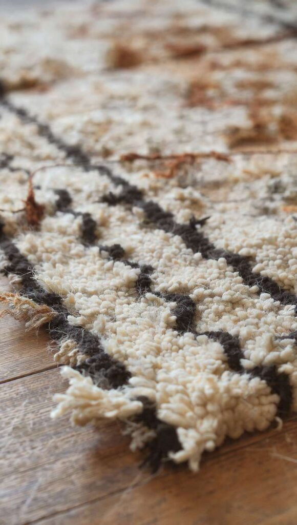 tappeto berbero vintage con rombi neri su pavimento in legno in soggiorno stile afrobohemien