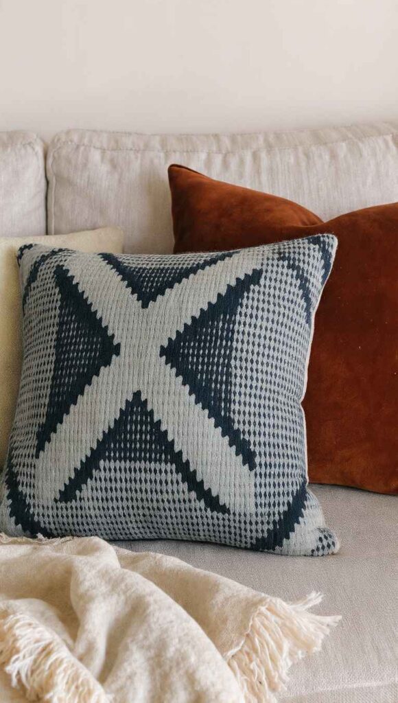due cuscini mudcloth bianco e nero e cuscino in velluto terracotta su divano lino stile afrobohemien