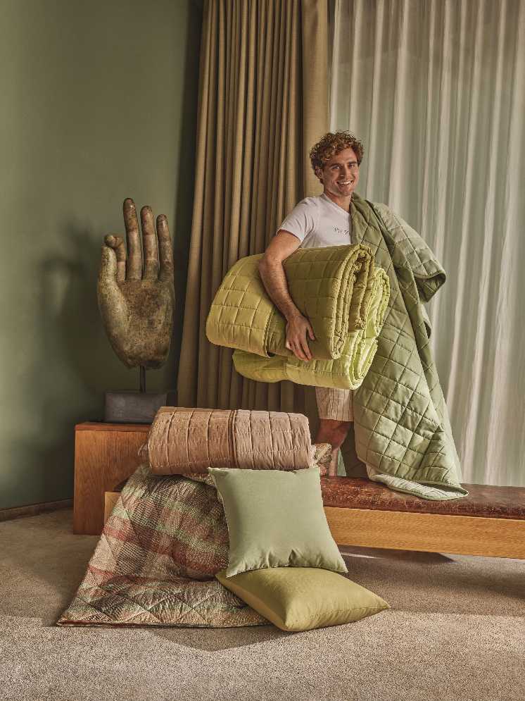 Uomo con trapunta leggera verde trapuntata e cuscini, home decor con scultura a mano e tessili colorati
