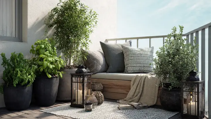 Balcone con panca contenitore e vasi di erbe aromatiche Balcone piccolo con panca contenitore in legno, cuscini, lanterne e vasi con basilico e erbe aromatiche
