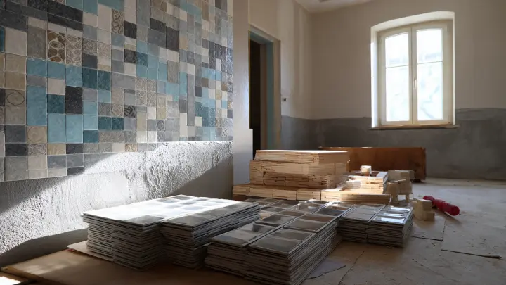 Casa in ristrutturazione con parete piastrellata a metà e materiali da lavoro