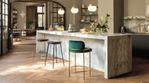Isola cucina in marmo con tre sgabelli vintage, due in metallo nero industriale e uno in velluto verde con struttura dorata