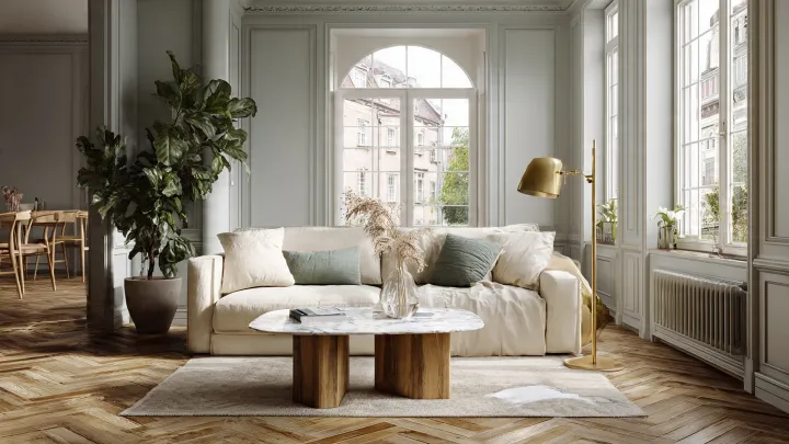 Soggiorno scandinavo grigio perla con parquet rovere, divano avorio e dettagli japandi Soggiorno scandinavo e japandi con pareti grigio perla, parquet in rovere naturale a spina di pesce, divano grande in lino avorio, tavolino in marmo bianco, lampada in ottone spazzolato, cuscini verde salvia e grande pianta da interno con luce naturale.