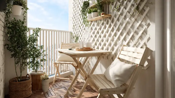 Balcone con grigliato bianco e mensole porta piante Balcone piccolo con grigliato in legno bianco, mensole a muro con piante e tavolino pieghevole con cuscini