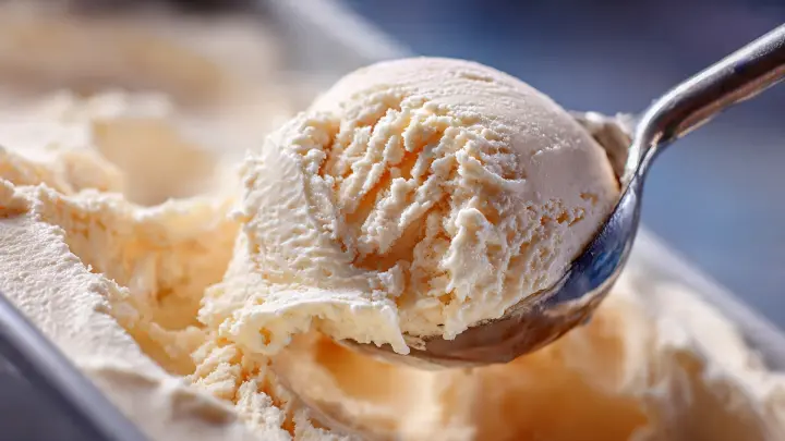 Primo piano di una pallina di gelato alla vaniglia fatto in casa, cremoso e senza cristalli di ghiaccio, prelevato con un cucchiaio