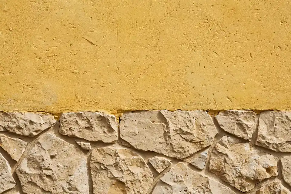 Dettaglio facciata casa gialla con pietra a vista Dettaglio casa gialla con pietra a vista e intonaco materico giallo caldo con fughe sottili beige
