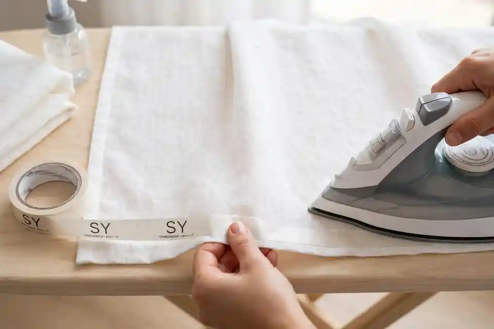 Come accorciare tende IKEA troppo lunghe con nastro SY Come accorciare tende IKEA troppo lunghe con nastro termoadesivo SY e ferro da stiro su asse da stiro in legno chiaro