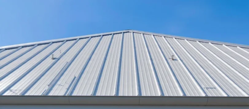 Inquadratura esterna di un tetto moderno in lamiera su casa indipendente, con cielo azzurro e sole pieno
