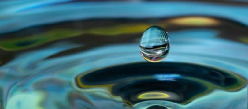 water drop falling and impacting on a body of water close u
