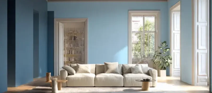 Soggiorno classico moderno con pareti color celeste e azzurro chiaro, grande divano bianco, parquet a spina di pesce e finestre luminose
